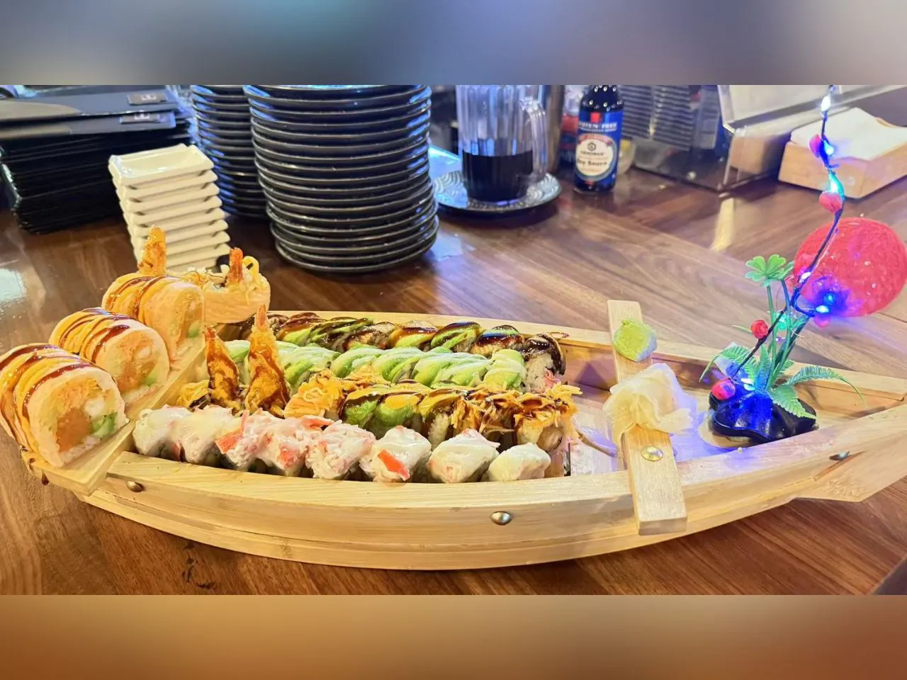 A variety of sushi served on a wooden boat - shaped platter at Koi Ramen&Sushi, a Japanese restaurant in Hutchinson